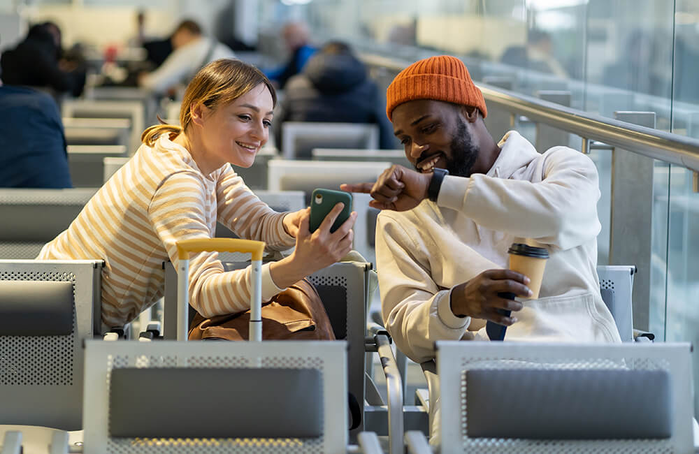 Happy couple waiting at the airport with their luggage